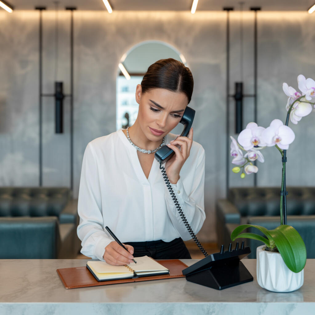 Receptionist calmly handling client calls after staff walkout — part of the 24-Hour Team Crisis Plan for salons and barbershops to protect revenue, client trust, and appointment continuity.